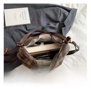 Detail view of the spacious inner compartment of the brown plaid shoulder bag