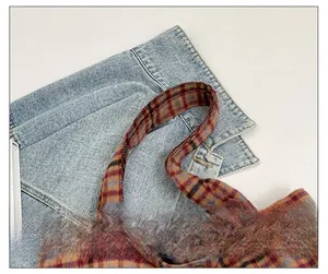 Close-up of wide strap and red-brown plaid texture on a stylish crossbody bag