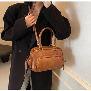 Brown faux leather handbag detail showing vintage texture and adjustable strap on model