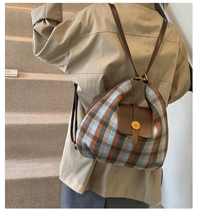 Detail of plaid texture and leather flap with gold logo clasp on a stylish backpack