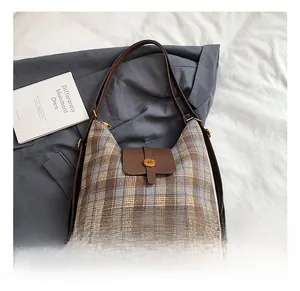 Detailed view of vintage plaid pattern fabric and brown leather strap on a shoulder bag