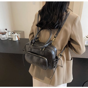 Detail of vintage black leather bag with gold hardware in a coffee shop setting