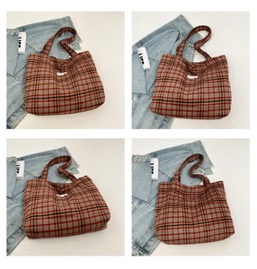 Detail of the reddish-brown plaid fabric texture and button closure on a tote bag