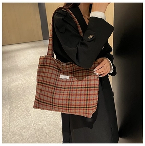 Detail of vintage plaid tote bag with heavy fabric texture and shoulder strap on model
