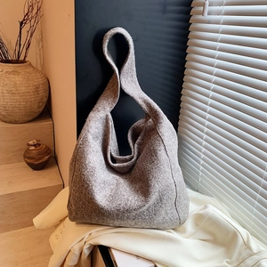 Détail du cabas en feutre gris avec tissu texturé sur fond d'escalier minimaliste en bois