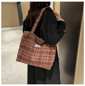 Retro orange plaid tote bag with shoulder strap shown on a model in a long black coat