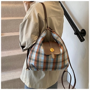 Detail of tweed quilted backpack with brown leather strap and golden N-buckle