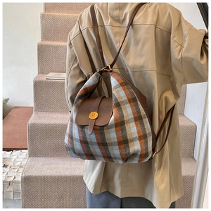 Close-up of a vintage plaid backpack with a metallic N buckle and premium leather trim