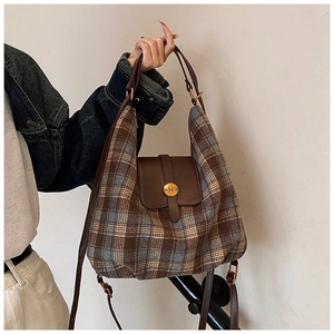 Detail of vintage tartan pattern fabric and brown leather handle on woman tote bag