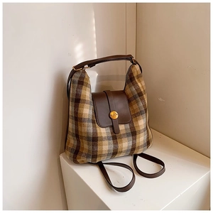 Close-up of vintage plaid underarm bag with brown leather flap and golden M-buckle