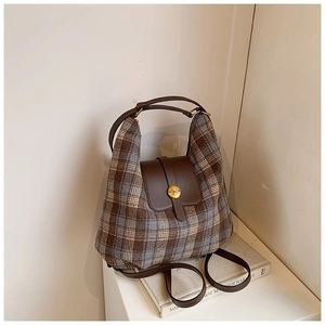 Close-up of retro plaid pattern and brown leather trim on vintage-style backpack