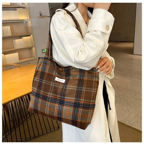 Detail of vintage plaid tote bag in brown and blue with brand tag on model in study