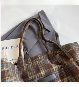 Detailansicht des braun karierten Shopper-Griffs und des weichen Wollstoffes der Tasche