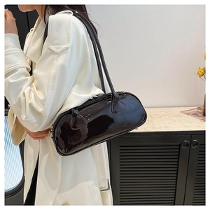 Sac bandoulière minimaliste en cuir verni marron foncé porté avec un trench blanc