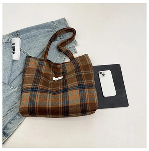 Detailed top view of plaid tote bag with brown buttons, books, and lifestyle items