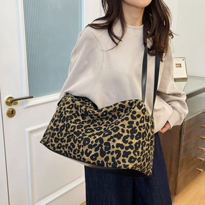 Close-up of a large tote bag featuring a wild leopard print pattern and black leather straps