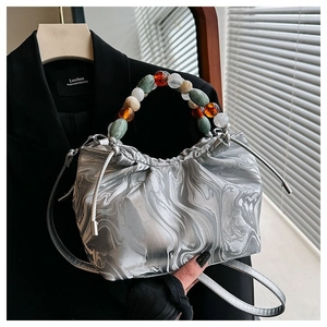 Detail der silbernen Marmor-Beuteltasche mit buntem Perlengriff und verstellbarem Schultergurt
