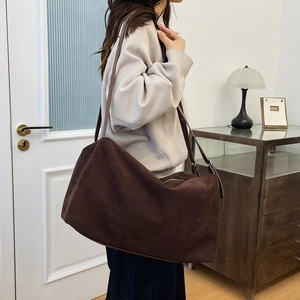 Brown suede shoulder bag with Boston style design worn by model in a minimalist room