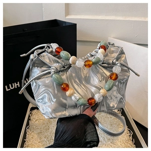 Detailansicht der silbernen Marmor-Tasche mit bunten Perlengriffen und Metallriemen