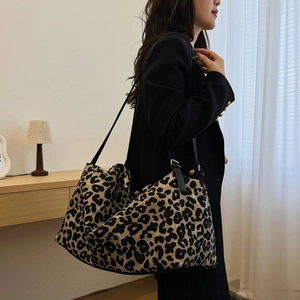 Close-up of leopard print tote bag with black leather straps worn by a model in black