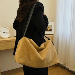 Brown suede hobo bag with black leather shoulder strap shown on a female model