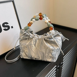 Detailansicht der silbernen Kordelzugtasche mit buntem Perlengriff und Marmormuster