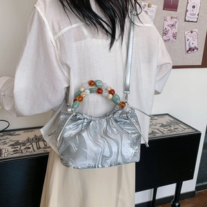 Nahaufnahme der plissierten silbernen Totebag mit buntem Perlengriff und Kordelzugverschluss