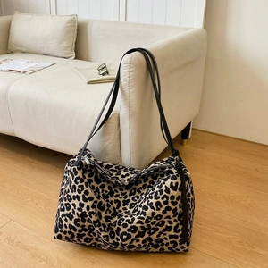Detail shot of leopard print canvas tote bag with black straps on a wooden floor
