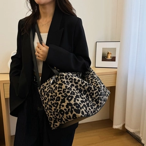 Close-up of leopard print tote bag with black faux leather strap on model's shoulder
