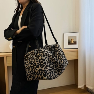 Leopard print tote bag with black leather handles shown on model for size and fit