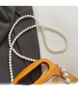Détail de la poignée en bois et bandoulière en perles blanches sur sac jacquard