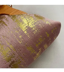 Vue macro du tissu en daim violet avec texture dorée et une poignée en bois lisse