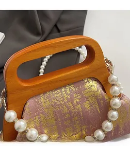 Détail du sac en tissu rose avec imprimé doré, poignée en bois et chaîne de perles