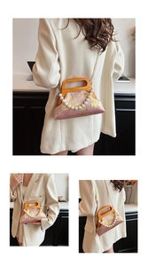 Gros plan du sac bandoulière rose avec texture dorée et poignée en bois courbé