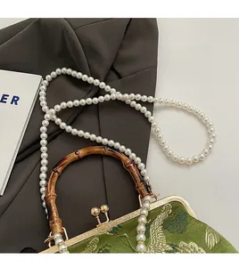 Detail of green brocade bag with crane embroidery, bamboo handle and pearl chain strap