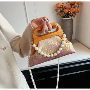 Détail du sac bandoulière en tissu rose avec poignée en bois et sangle en perles