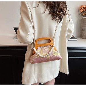 Détail du sac en tissu rose à paillettes dorées, poignée en bois et chaîne de perles