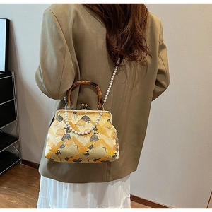 Detail of vintage bird embroidery purse with bamboo handle and pearl shoulder strap