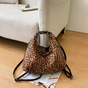 Detail of leopard print shoulder bag with adjustable brown straps on wooden floor