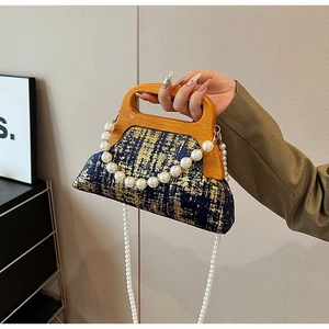 Détail d'un sac en tweed bleu et or avec poignée en bois en U et bandoulière en perles