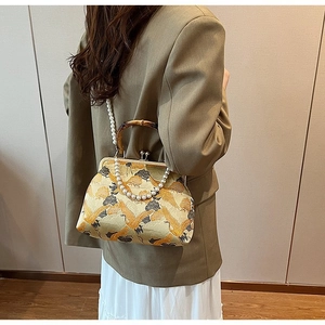 Detail view of brocade handbag featuring crane patterns and natural bamboo handles
