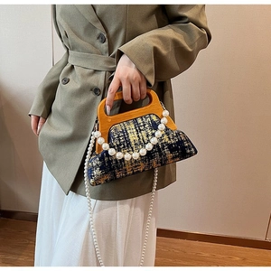Détail d'un sac vintage en tissu avec poignée en bois et chaîne de perles élégante