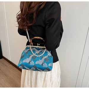 Detailed shot of blue crane brocade handbag with bamboo handle and pearl chain strap