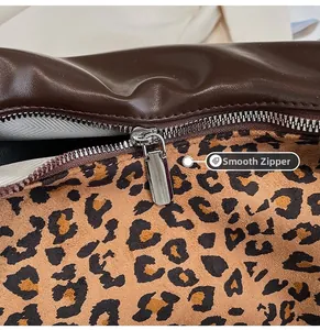 Detail view of the smooth silver zipper and leopard print lining on the brown leather bag