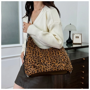 Detail of leopard print tote bag with brown leather straps shown in a modern interior
