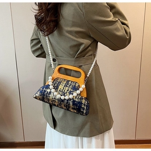 Détail du sac en brocart bleu marine avec poignée en bois et bandoulière en perles