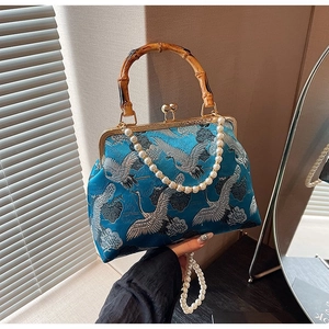 Detail of blue satin handbag with crane embroidery, bamboo handle and pearl chain