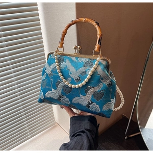Detailed close-up of retro blue brocade handbag with crane embroidery and bamboo handle