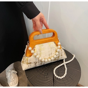 Détail du sac minimaliste avec texture de feuille d'or et poignée en bois massif