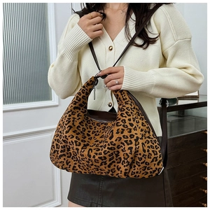 Detailed close-up of leopard print shoulder bag with brown leather strap and metal buckle